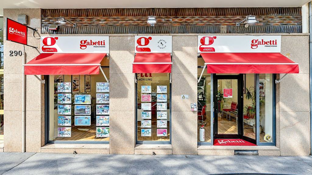 Facciata dell'agenzia Gabetti Torino Parella in Corso Francia 290 con le tende rosse e le vetrine degli annunci